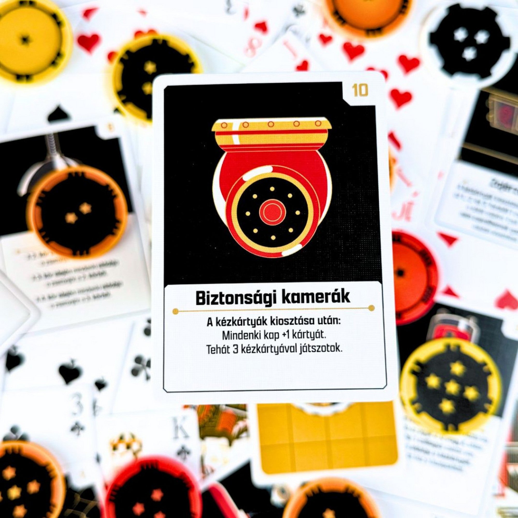 The Gang kooperatív pókerjáték eseménykártyája „Biztonsági kamerák” felirattal, háttérben játékkártyák és zsetonok.