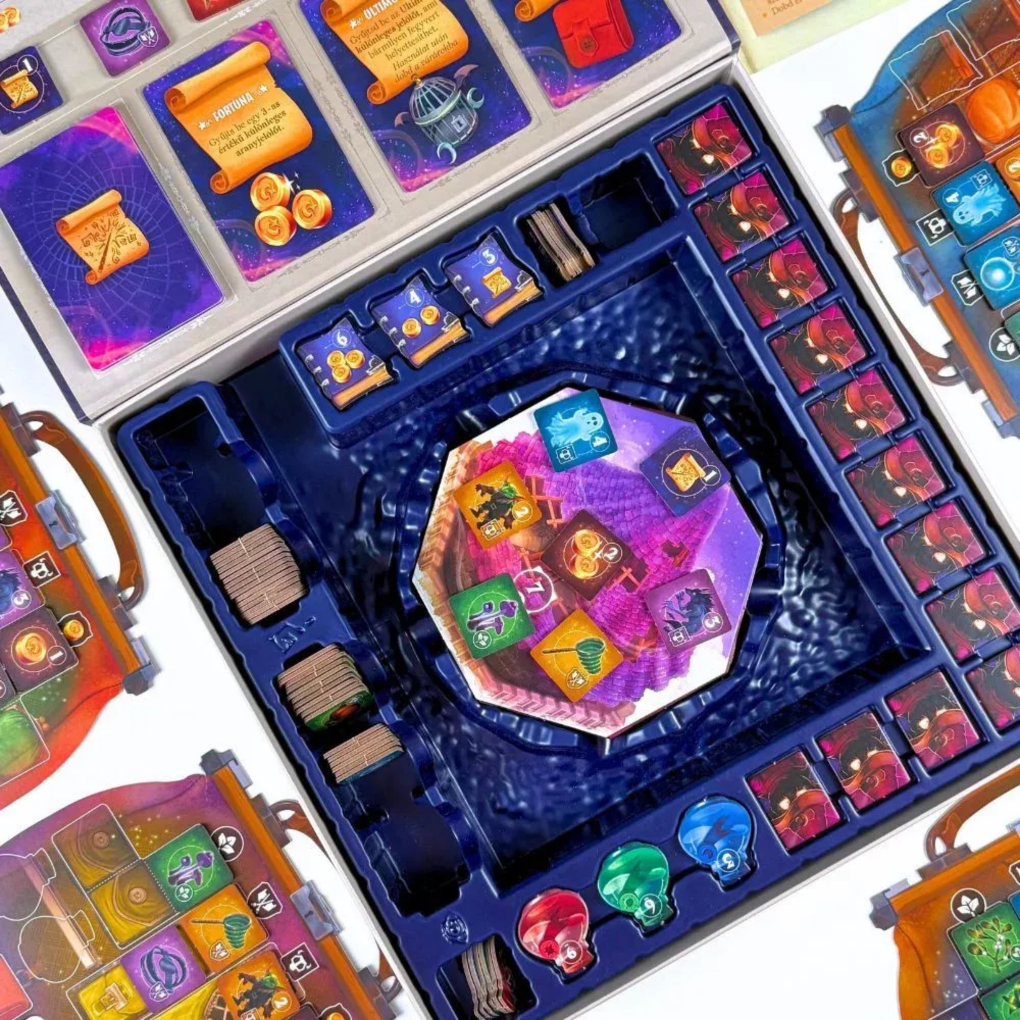 Varázstorony társasjáték asztalkép felülnézetből, középen a sokszög alakú toronymezővel, körülötte a színes játékos táblákkal, kártyákkal, zsetonokkal és mágikus ikonokkal.