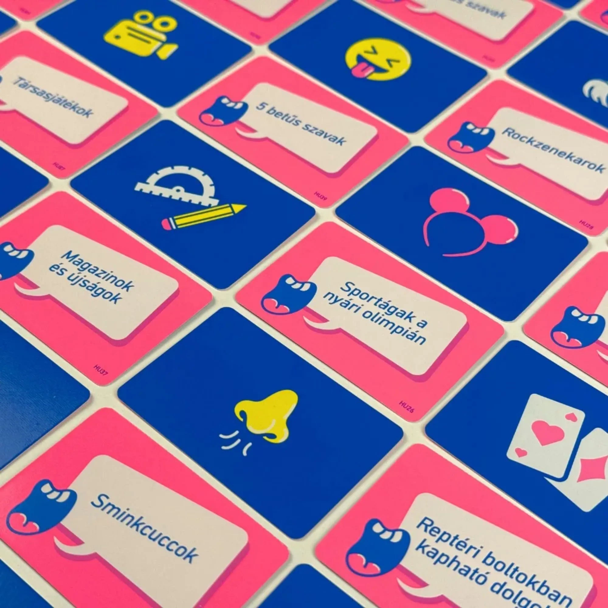 Zajos siker társasjáték kártyái részletfotón, különböző témájú feladatokkal, magyar nyelvű szövegekkel és egyszerű, jól felismerhető ikonokkal színes háttéren.