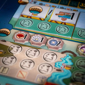 A fehér várkastély: Párbaj tábla zöld részlete akciómezőkkel, piros és fehér kagylóikonokkal és folyóábrázolással.