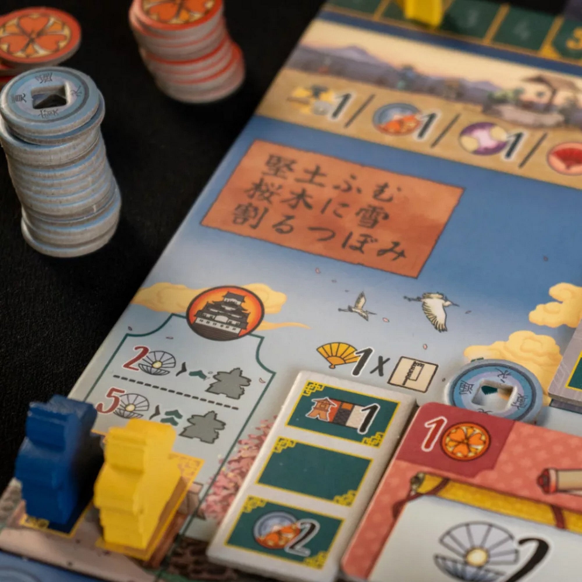 A fehér várkastély: Párbaj társasjáték táblája és zsetonjai részletes japán motívumokkal, különböző ikonokkal és színes jelölőkkel.