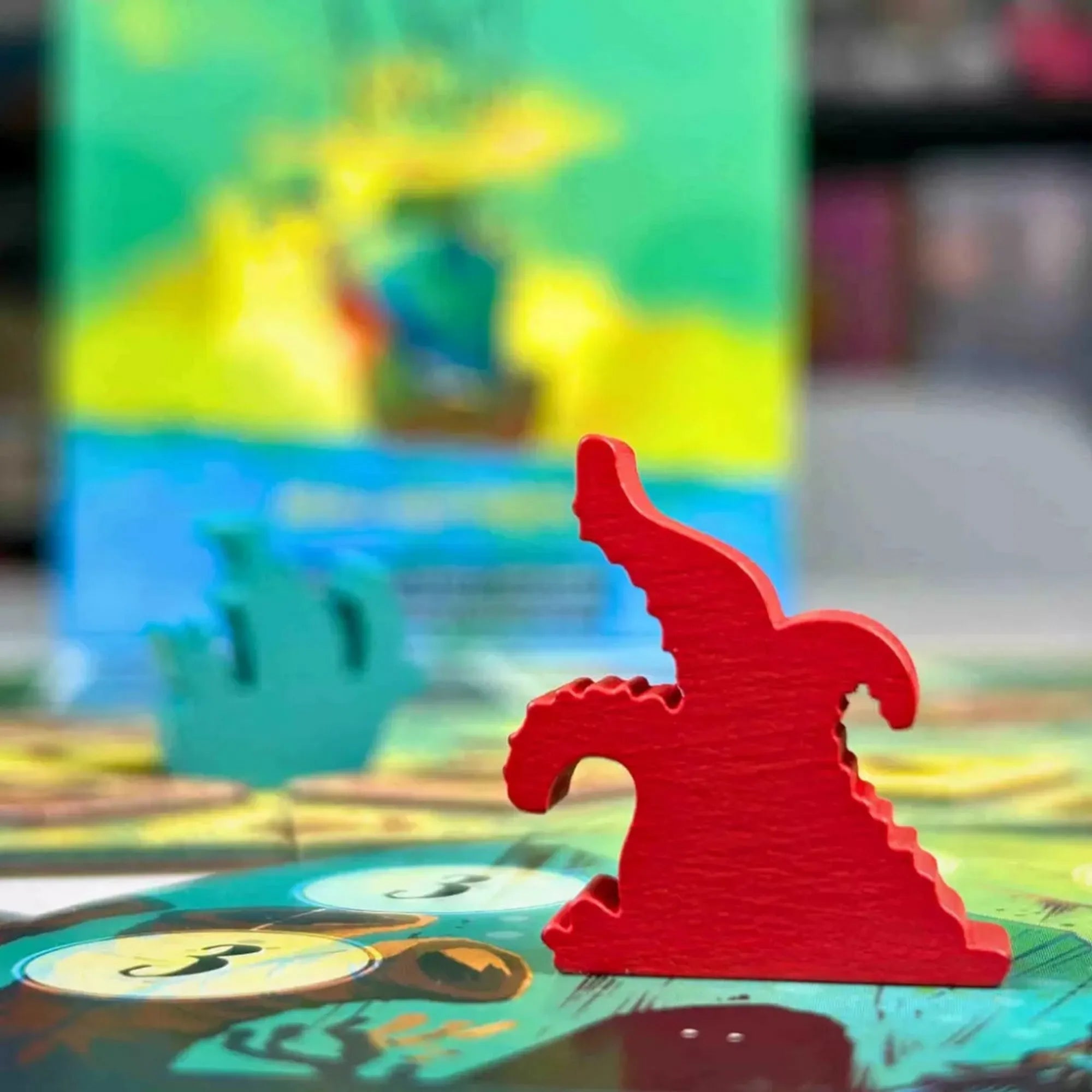 A nagy kékség társasjáték piros kraken figura közelről, a játéktábla és a doboz háttere előtt