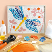 Atelier 72 mozaikkészítő felnőtteknek: Szitakötő – elkészült szitakötő mozaikkép virágmotívumokkal, az alkotáshoz használt eszközökkel körülvéve.