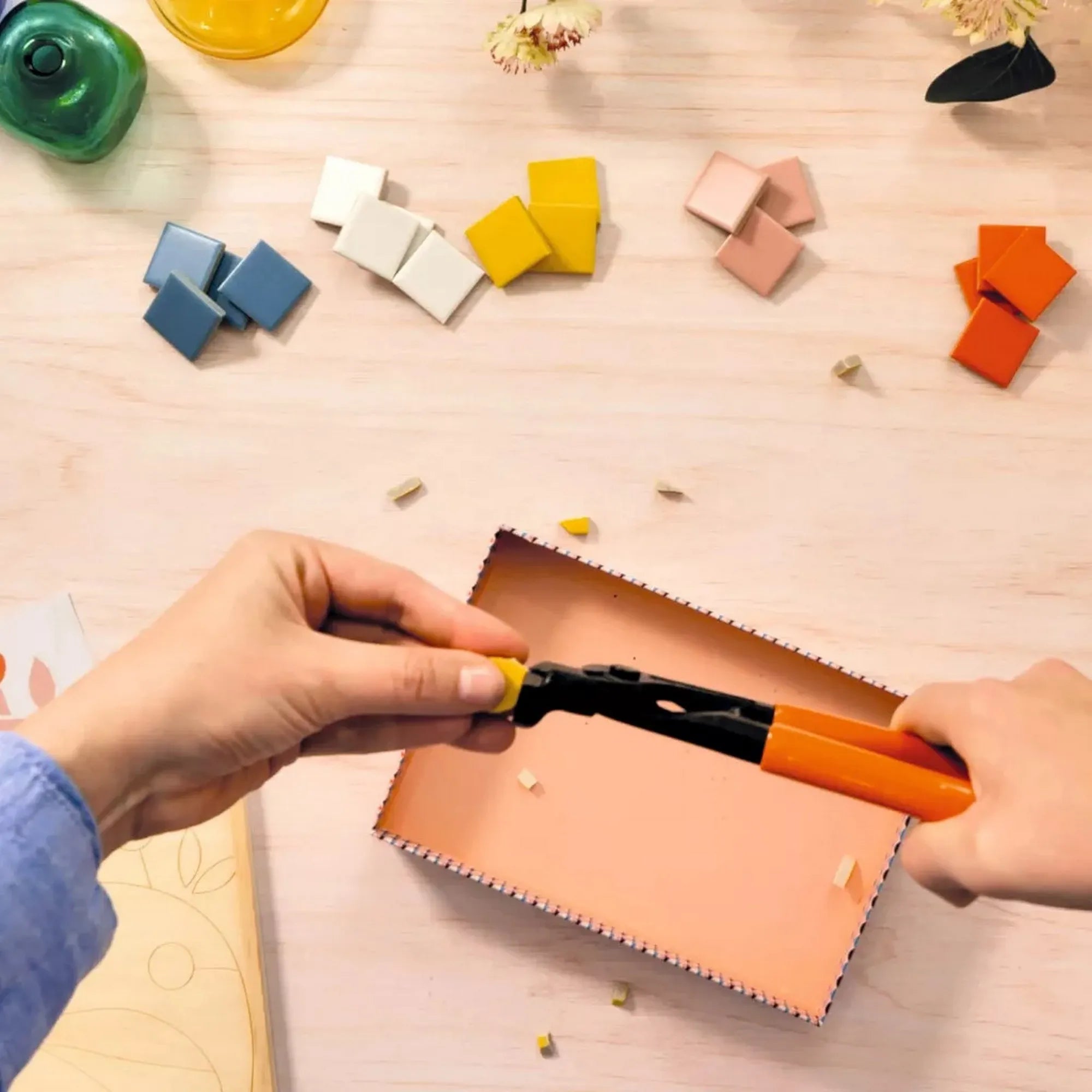 Atelier 72 mozaikkészítő felnőtteknek: Szitakötő – mozaiklapok darabolása fogóval, különböző színű elemek az asztalon.