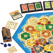 Catan játékmező közelről, láthatók a nyersanyaglapkák, városok, utak és fejlesztési kártyák. A részletes kivitelezés kiemeli a 2025-ös kiadás új dizájnját.