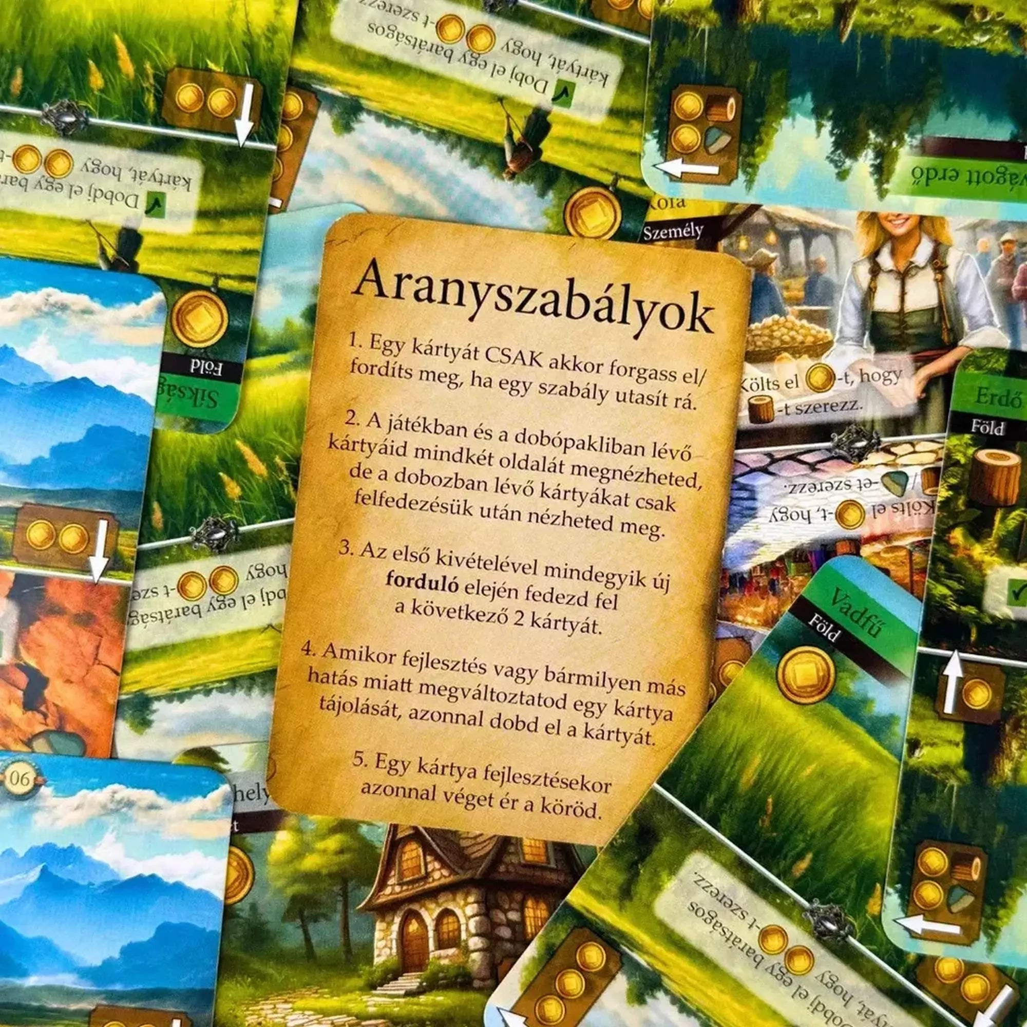 Az Egy királyság krónikája társasjáték kártyái szétszórva, középen az Aranyszabályok kártya olvasható.