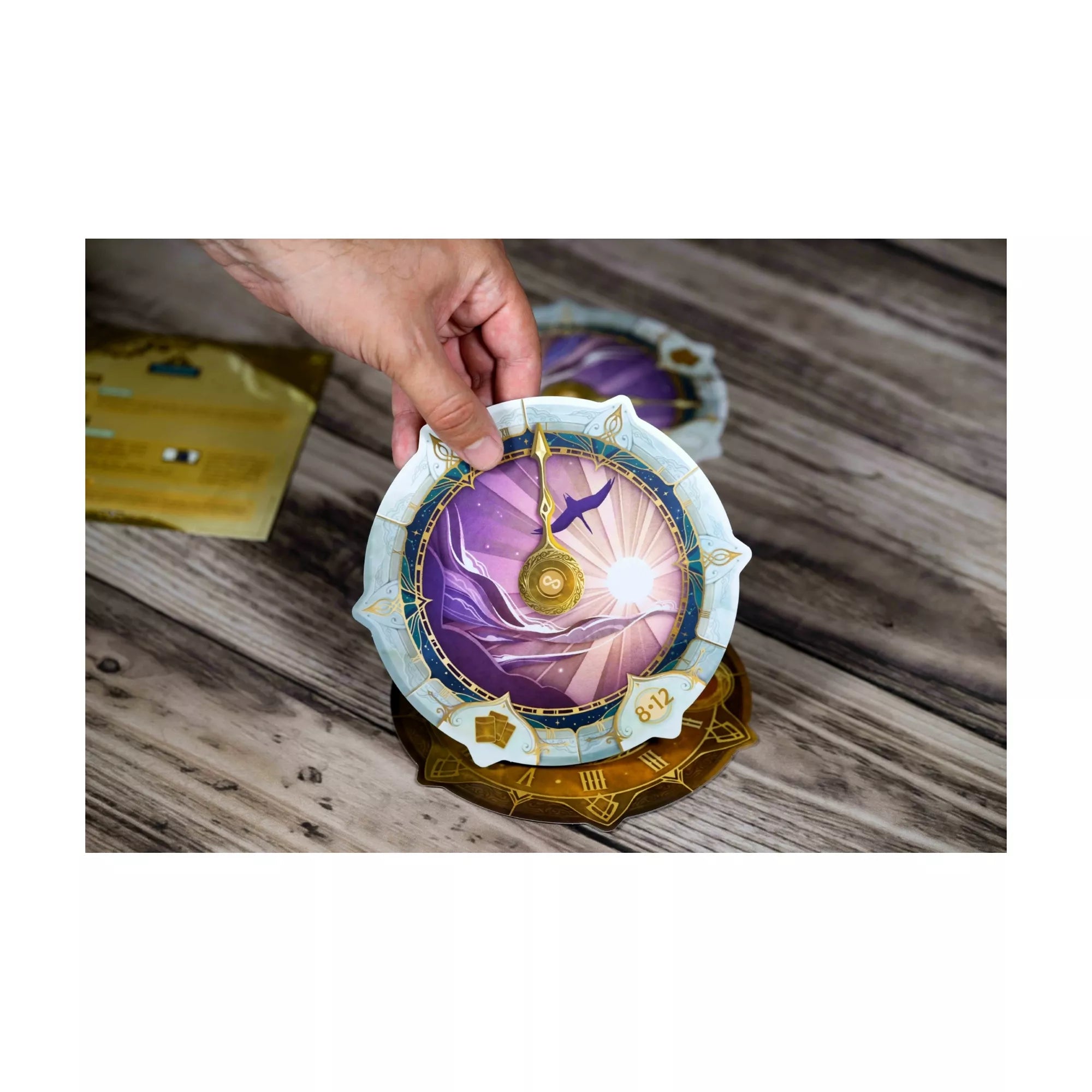 Egy játékos kezében az Időhurok csodaszép, arany mutatókkal és lila háttérrel díszített óratárcsája. A grafika a fény és az idő találkozását szimbolizálja.