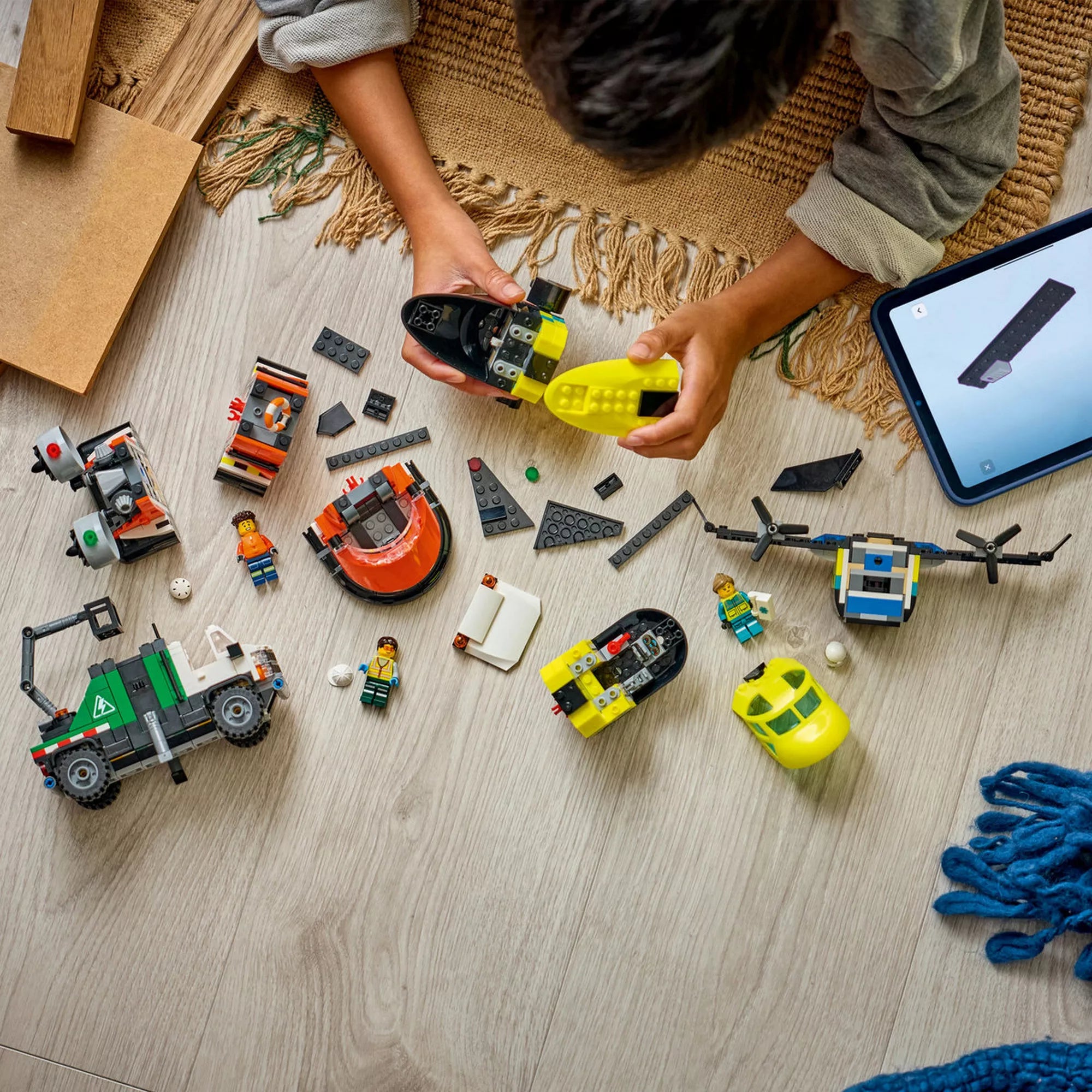 LEGO City 60505 készlet építés közben, szétszedett modulokkal, minifigurákkal és LEGO Builder alkalmazással tableten