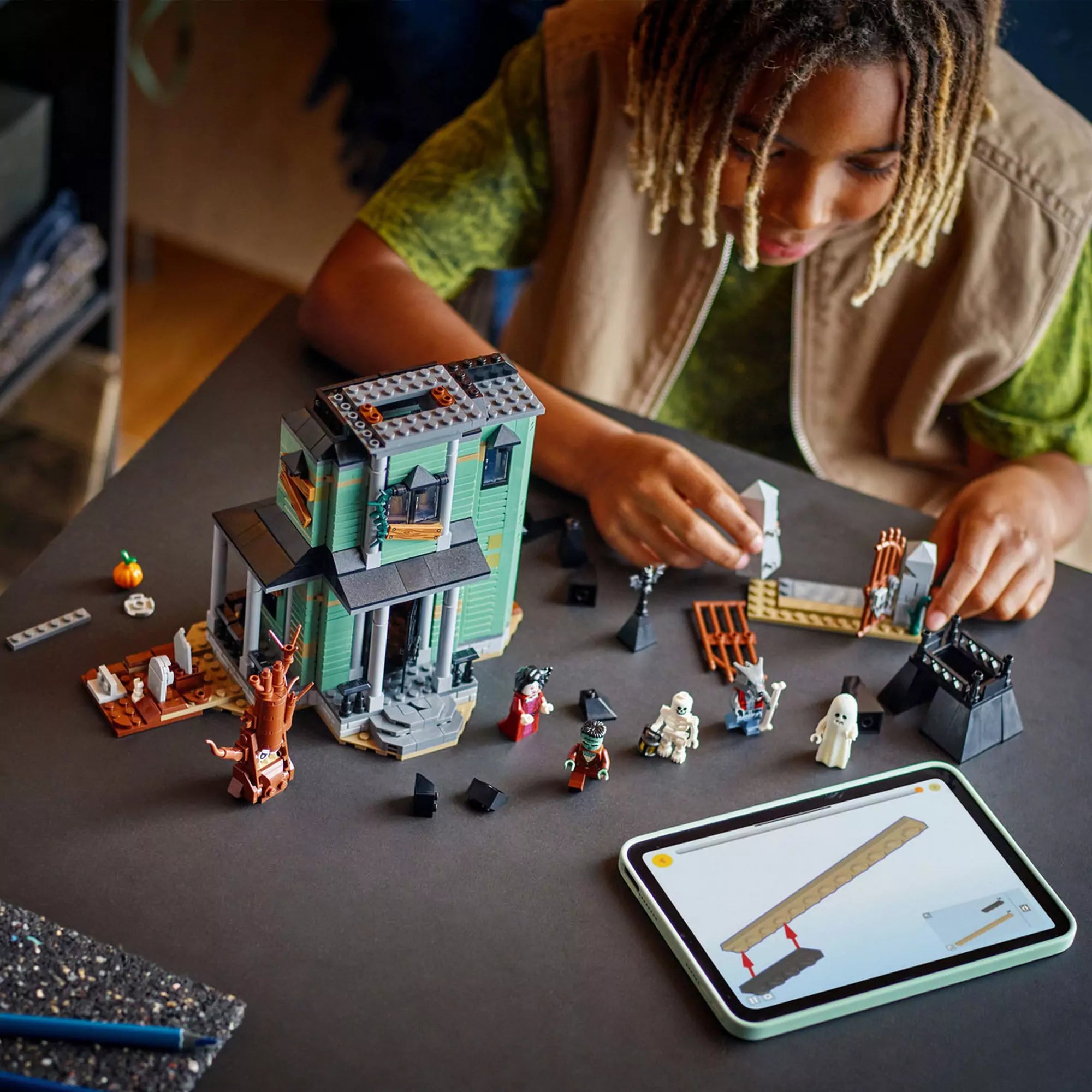 LEGO Creator Kísértetkastély (31167) építés közben – Egy gyermek az asztalnál építi a kísértetkastélyt, körülötte a figurák és kiegészítők.