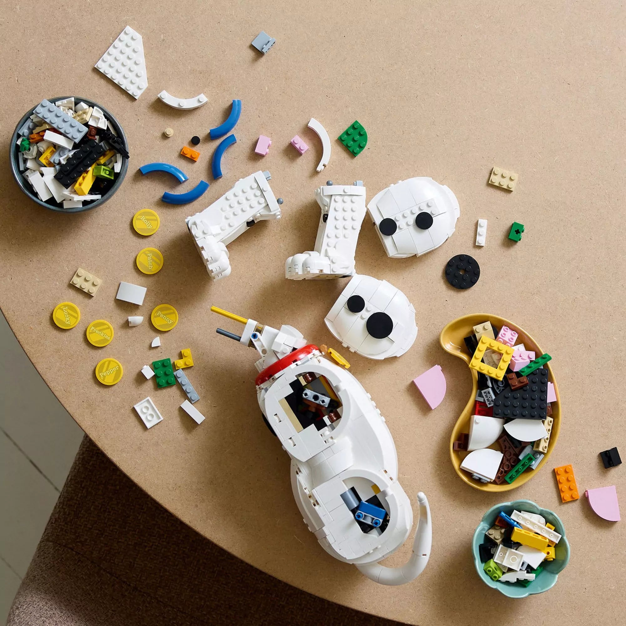  LEGO Disney 43269 Százegy kiskutya szett építés közben, a részegységek és LEGO elemek asztalra szórva láthatók.