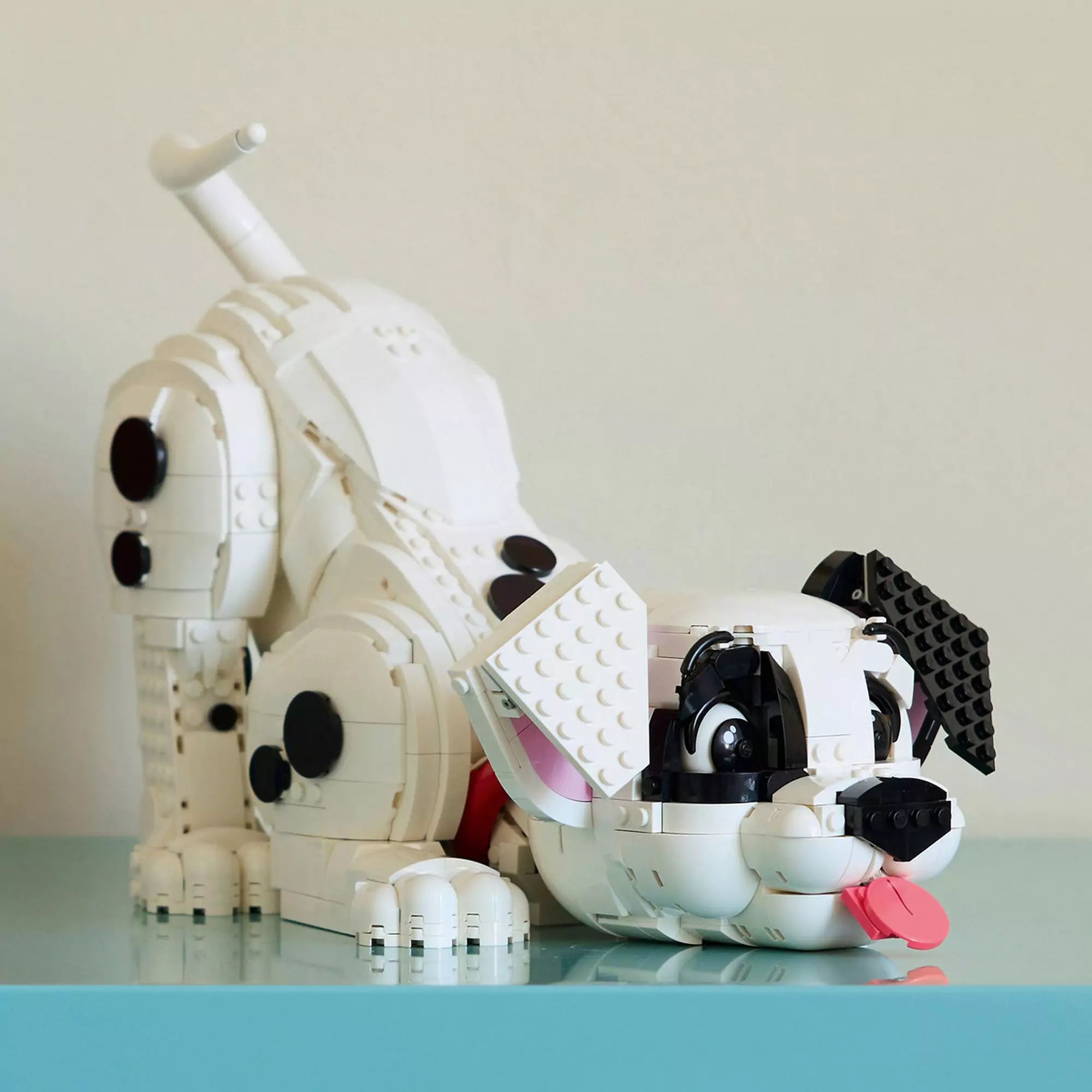 LEGO Disney 43269 Százegy kiskutya modell játékos, hasaló testhelyzetben kiállítva egy világoskék felületen.