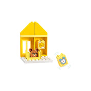 LEGO Duplo alvós házikó medvefigurával – A LEGO 10414 sárga házikója kisággyal és alvó medvével, mellette egy kakasos és egy ébresztőórás elem.