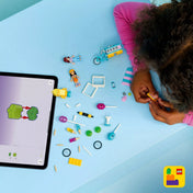 LEGO Friends Jégkrémes és lufis stand (42692) építőjáték elemei játék közben, szétszórt kiegészítőkkel, minifigurákkal és egy tablettel, amely digitális építési útmutatót mutat.