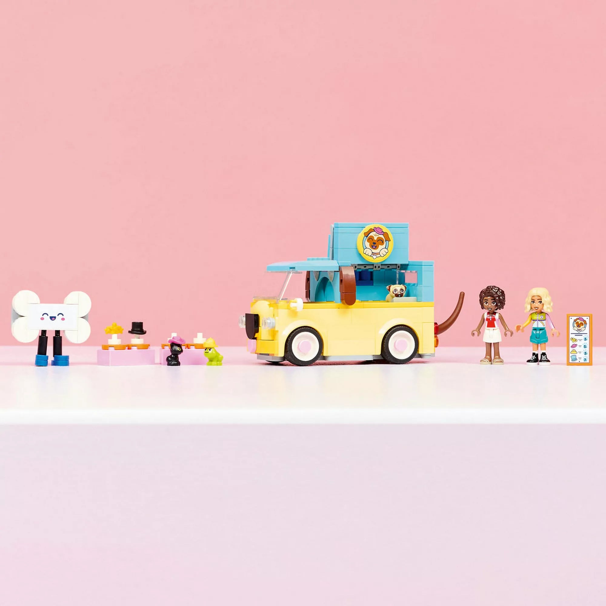 LEGO Friends mopsz formájú kisteherautó a figurákkal és kisállat-kiegészítőkkel, letisztult rózsaszín háttér előtt