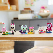 A LEGO® Gabby babaháza 11215 készlet hat cicakaraktere egy asztalon elrendezve, köztük Pisiréna, Cuki Dobozka, Tündérmiau, Panda Cica, Muffinka és DJ Cica.