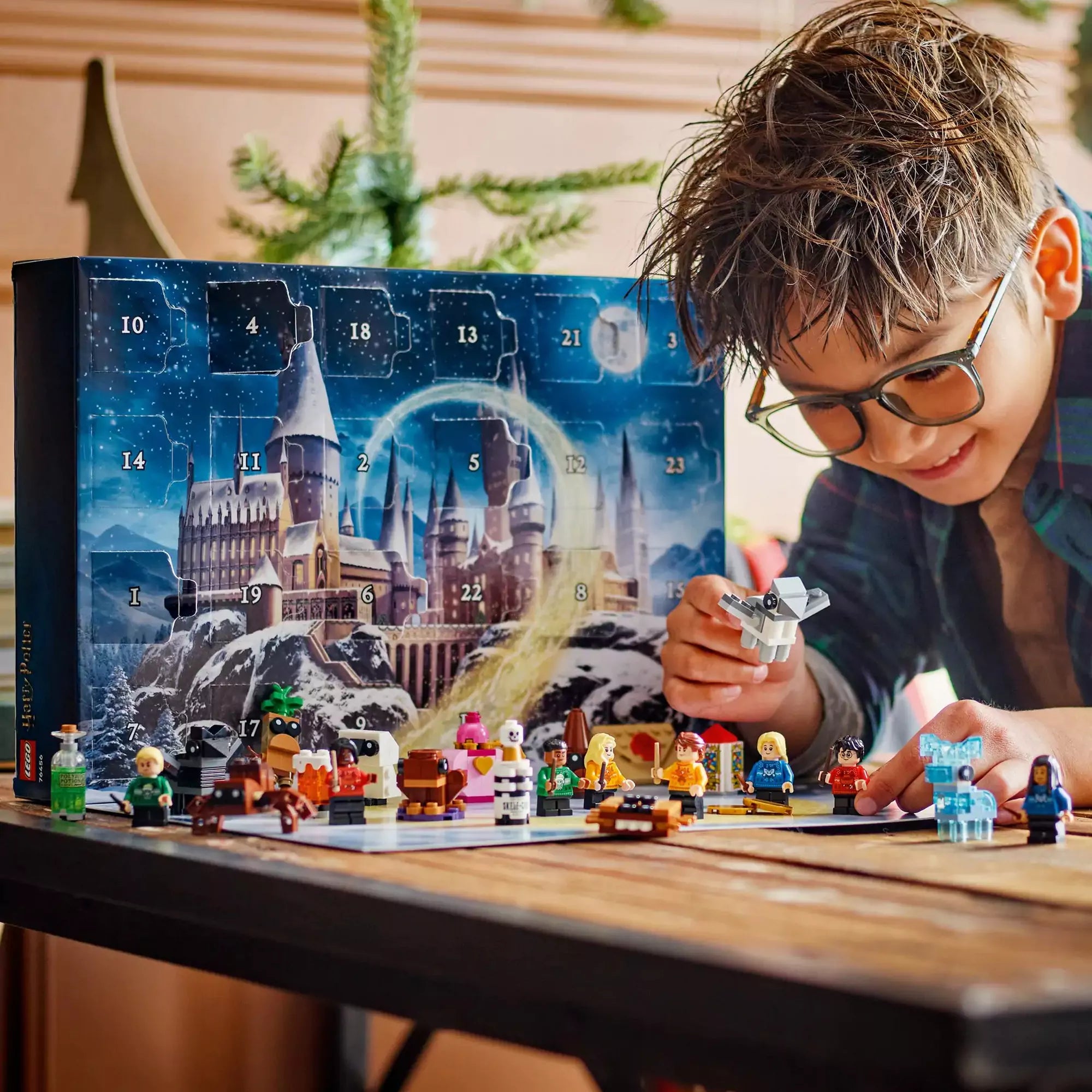 Egy kisfiú a LEGO Harry Potter Adventi naptár 2025 figuráival játszik, az ünnepi háttér előtt varázslatos minifigurákkal és építményekkel.