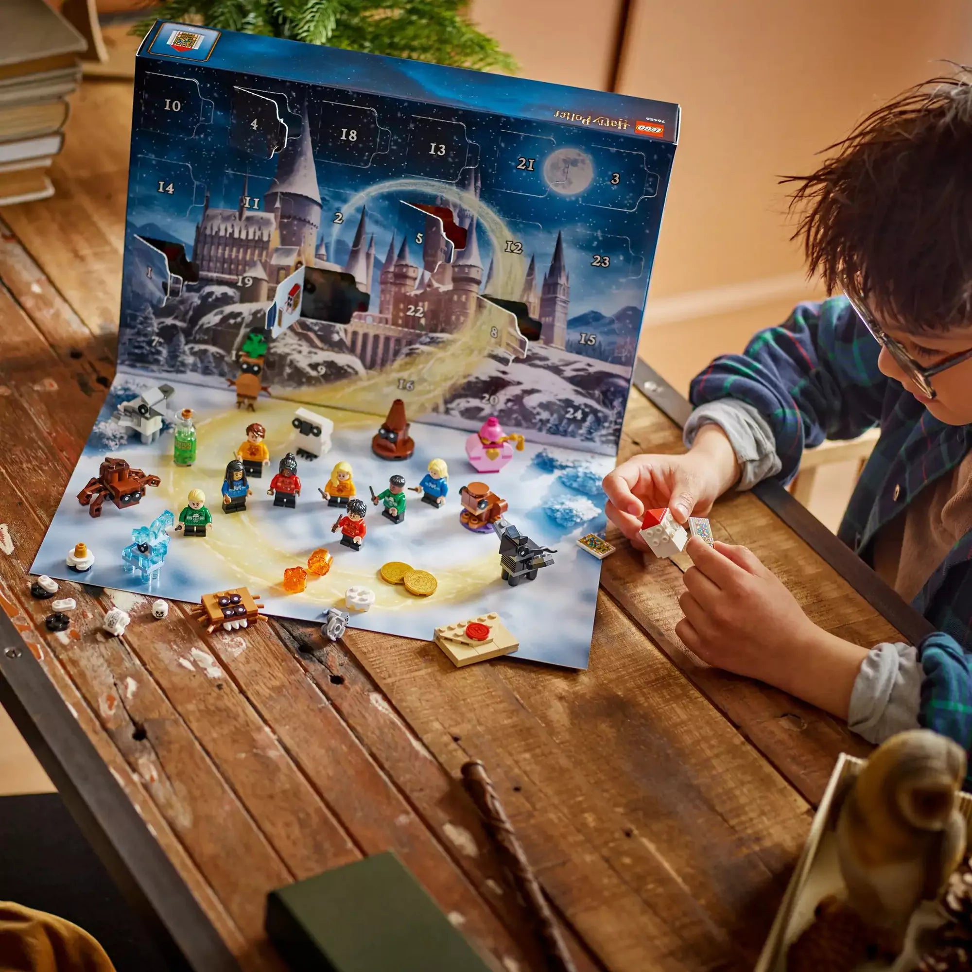 Gyerek játszik a LEGO Harry Potter Adventi naptár 2025 készlettel, a kinyitott naptárból előkerült figurákat és kiegészítőket helyezve el az asztalon.