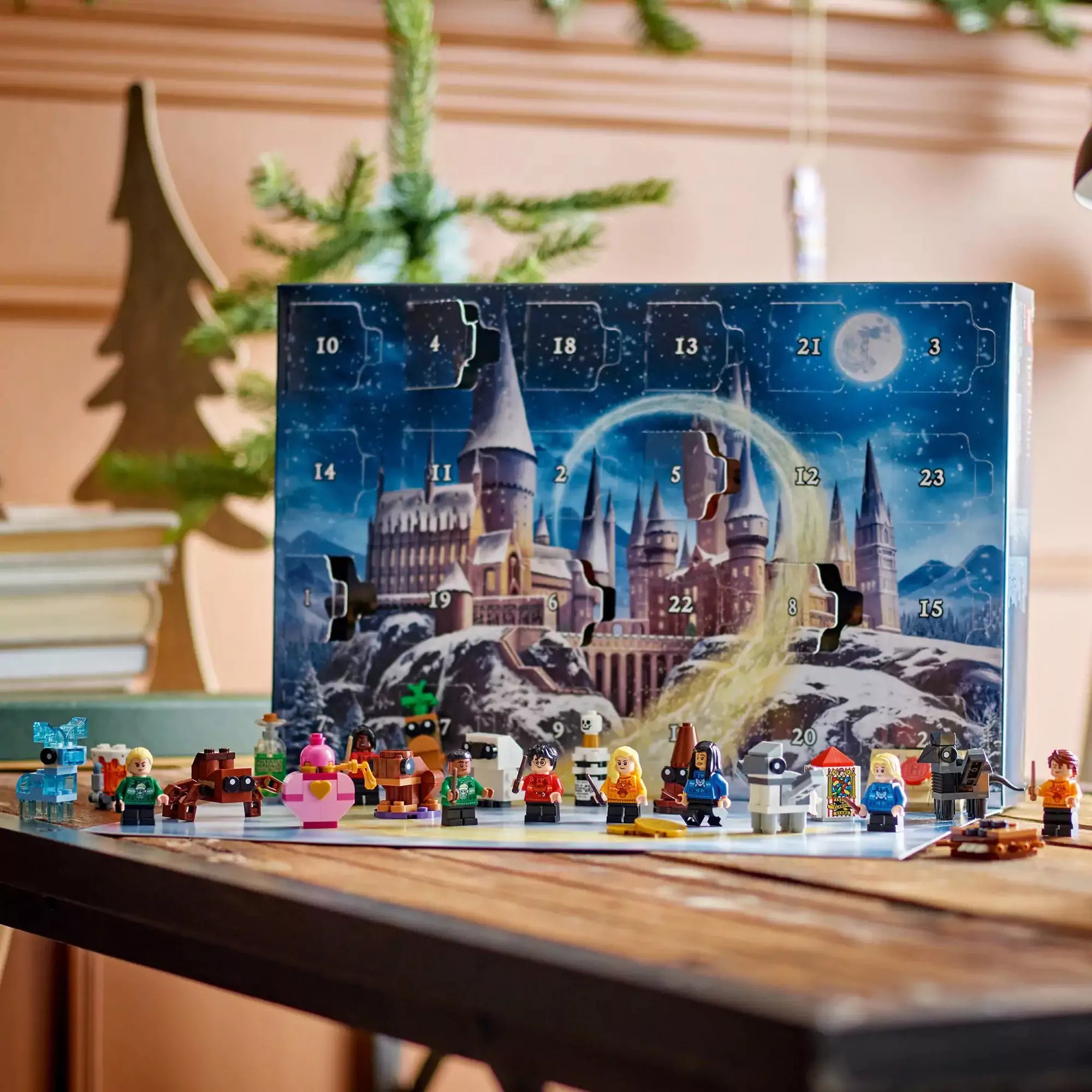LEGO Harry Potter Adventi naptár 2025 kinyitott állapotban, a téli Roxfort illusztráció előtt felállítva az összes minifigurával és kiegészítővel.