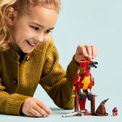 Egy mosolygó kislány játszik a megépített Fawkes főnix figurával, mellette a Teszlek Süveg, a kiállítóállvány és a kis madárfigura.
