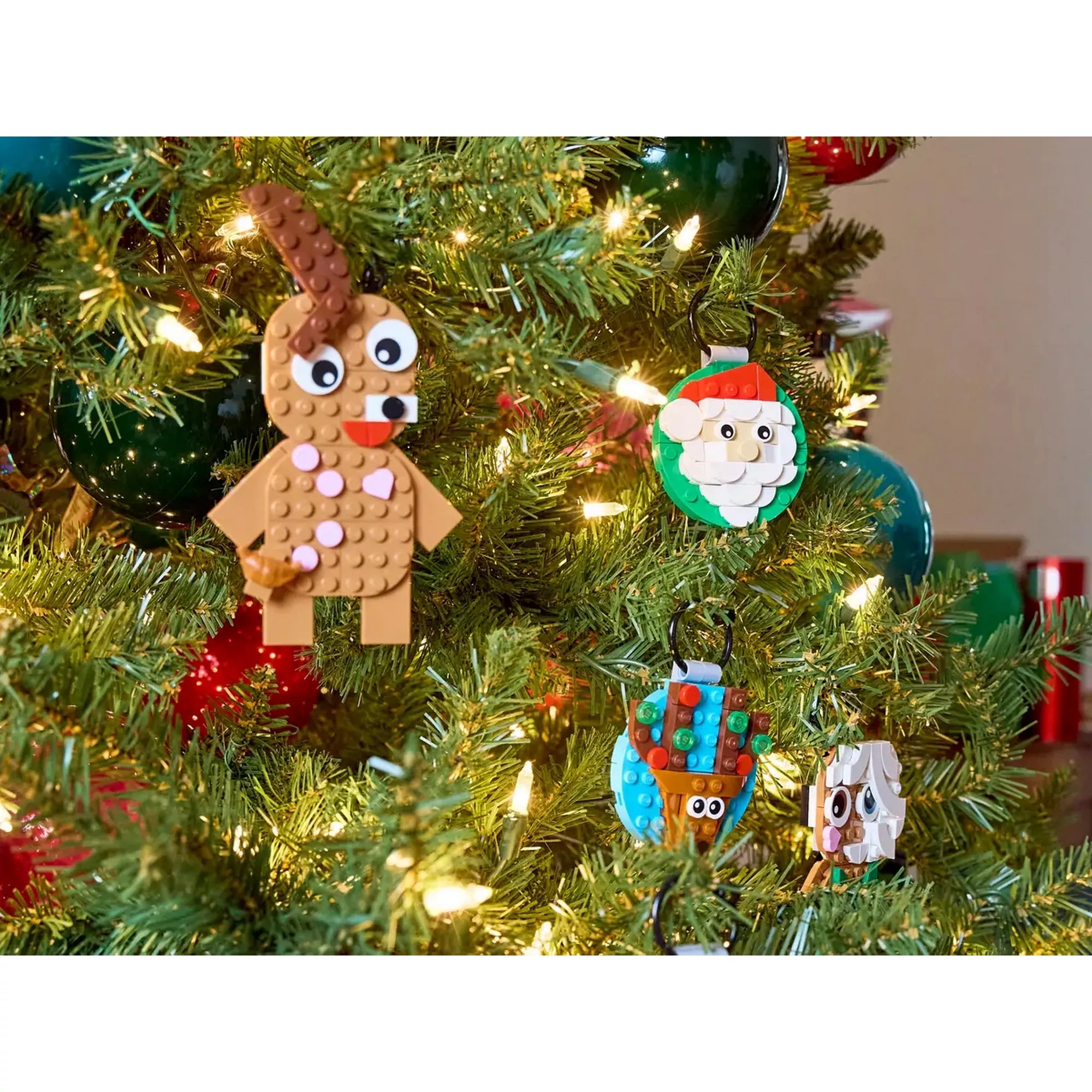 A LEGO Karácsonyi díszválogatás (40744) készlet színes díszei egy feldíszített karácsonyfán: látható a Mikulás, a hóember, az ajándék és a rénszarvas LEGO dekoráció.