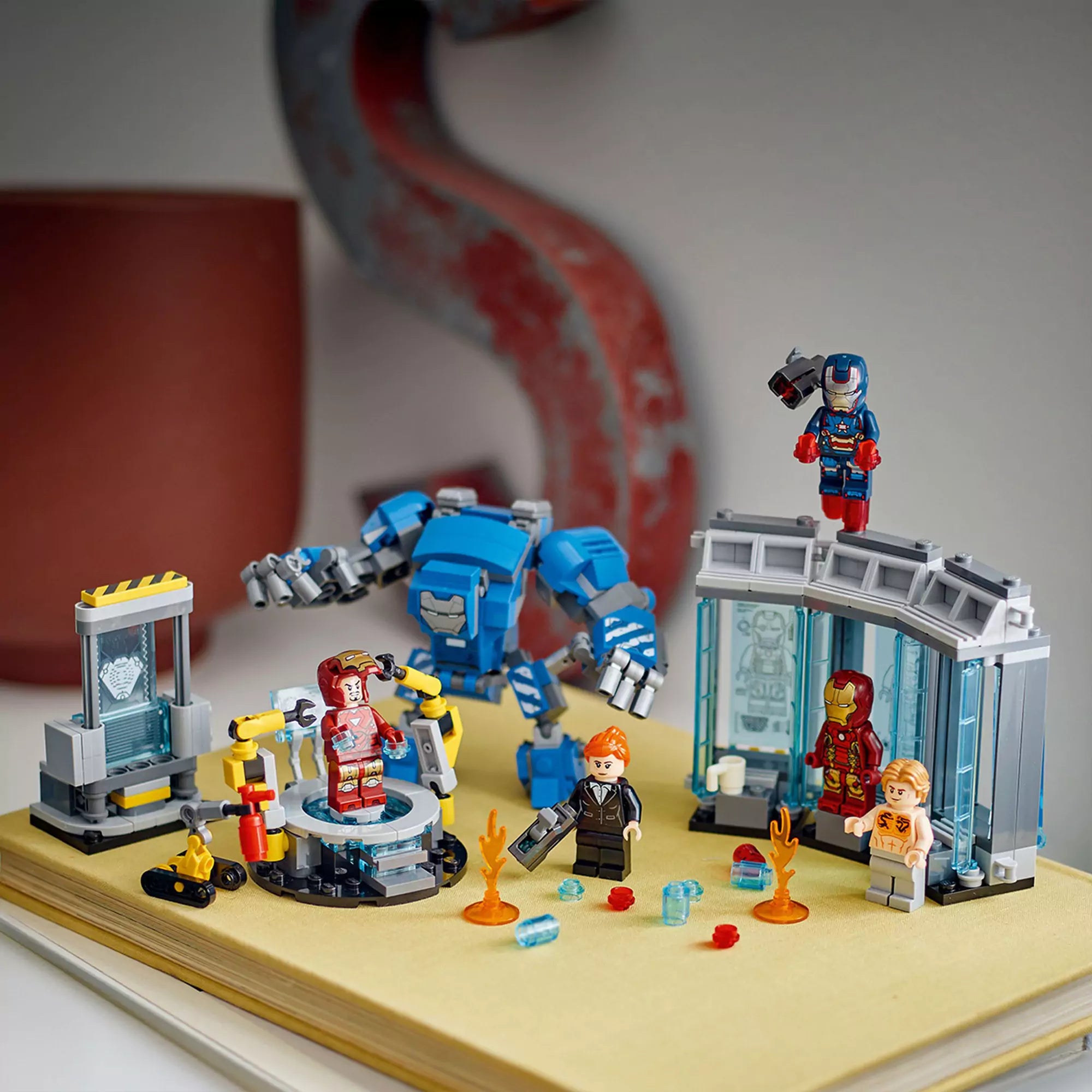 Kiállítva a LEGO Marvel A Vasember laboratóriuma: páncélcsarnok figurái és kiegészítő elemei egy könyvön.