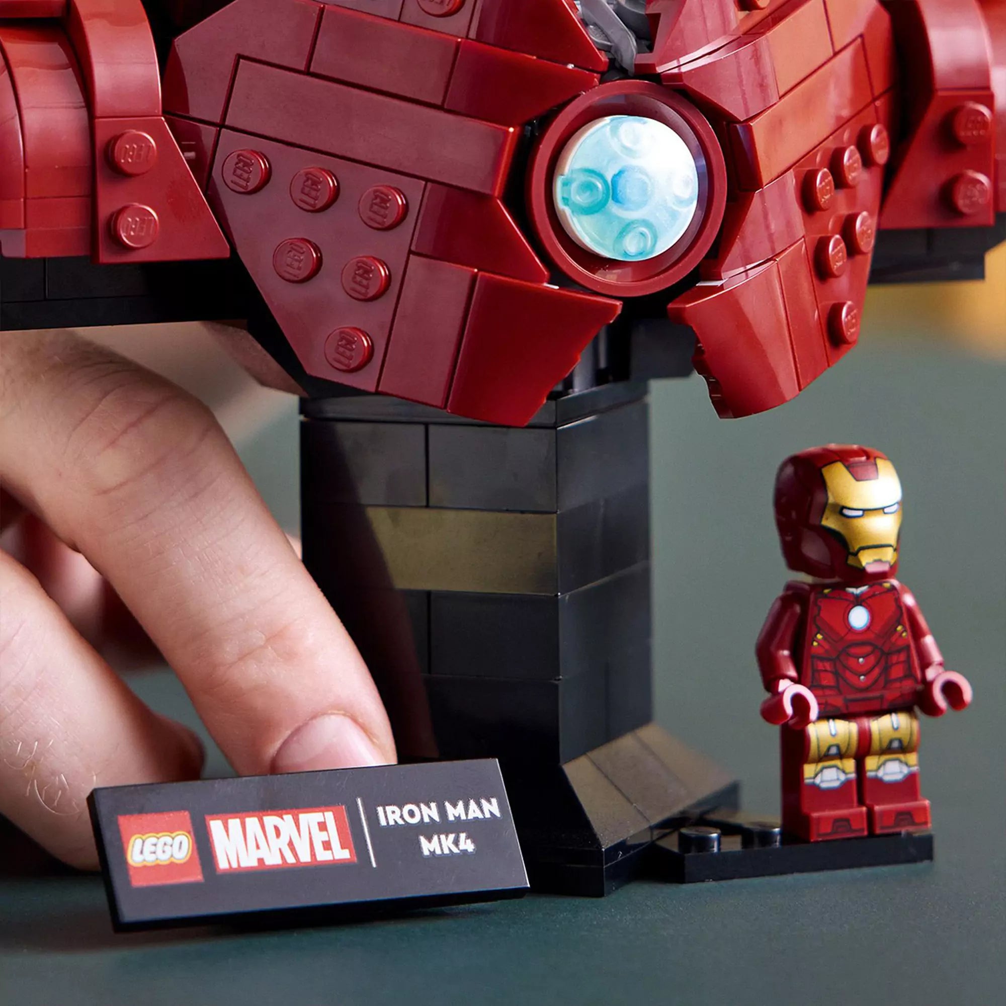 A LEGO Marvel Iron Man MK4 mellszobor (76327) talapzata közelről, előtte az információs tábla és egy klasszikus Iron Man minifigura.