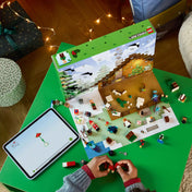 Gyermek játékközben a LEGO Minecraft Adventi naptárral – a doboz, a kinyitott ablakok, számos minifigura és apró építmény látható asztalon kiterítve.