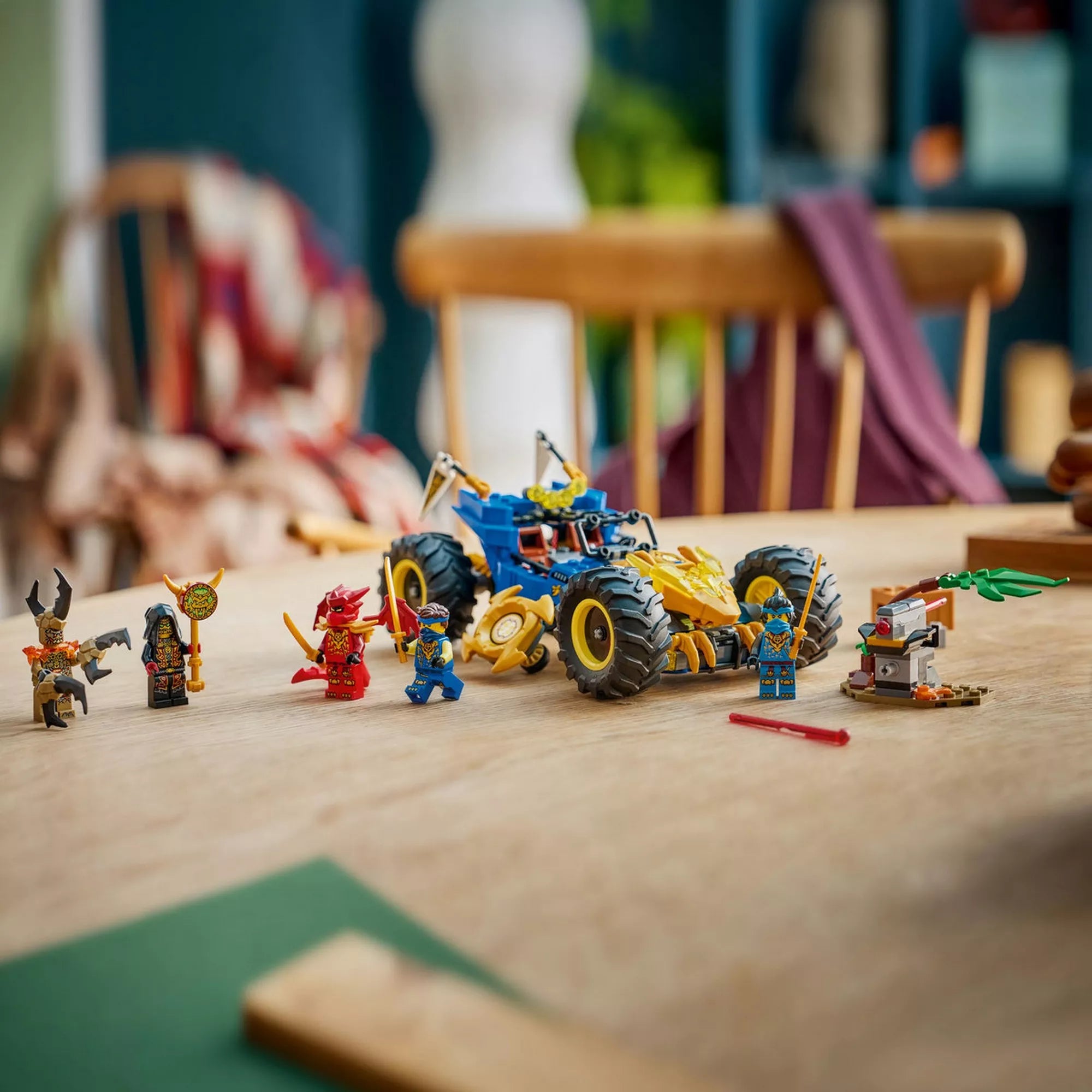 A LEGO NINJAGO Jay átalakuló járműve összeépítve, az asztalon elrendezett minifigurákkal és kiegészítő elemekkel, valós játékkörnyezetben, filmes hangulatú háttérrel.