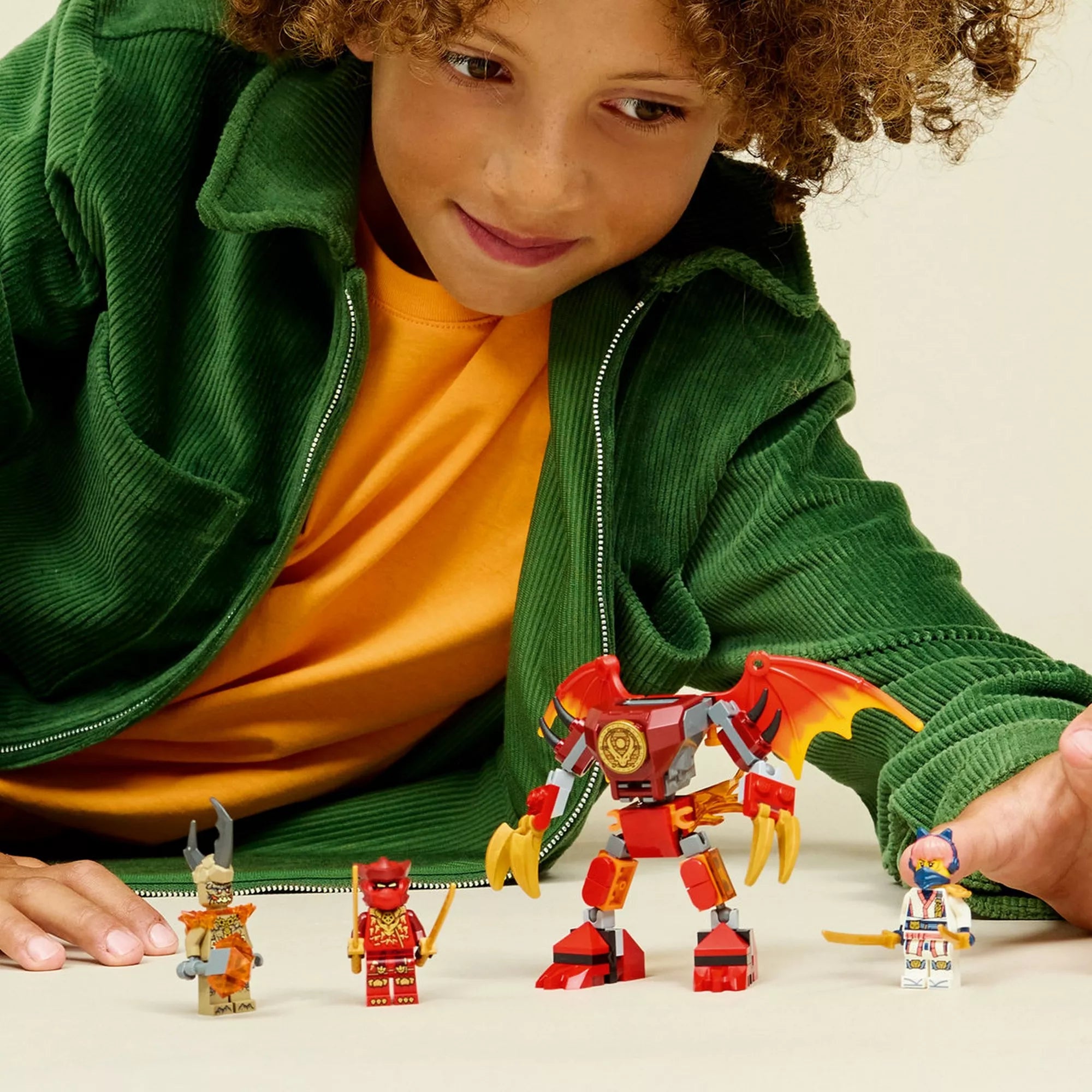 Gyermek játék közben a LEGO NINJAGO Kai’s Dragon Mech Battle Pack figuráival és a sárkány mech modellel.