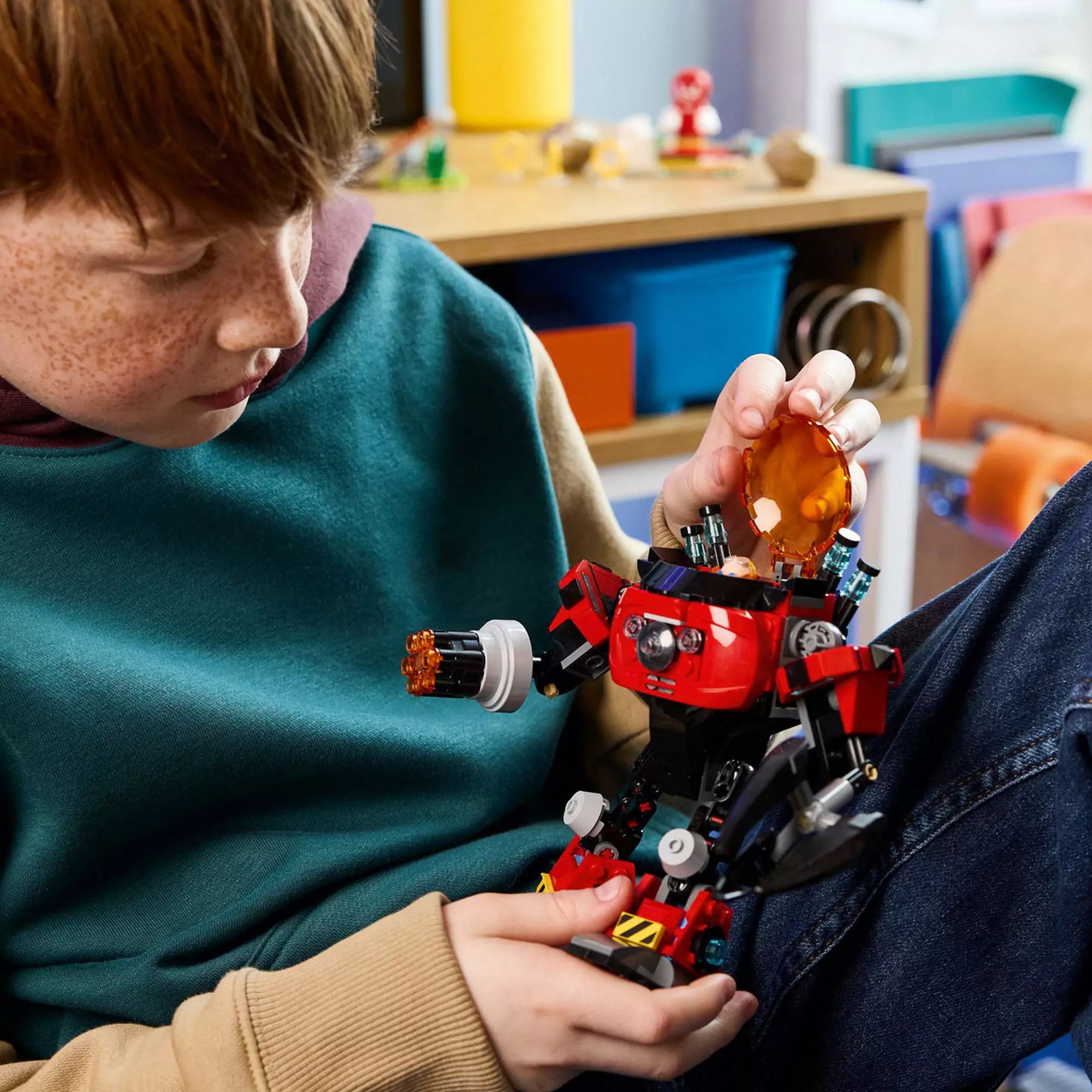 Gyerek a LEGO 77005 Egg Crusher Mech tetejét nyitja, miközben kézben tartja a piros robotot játék közben.