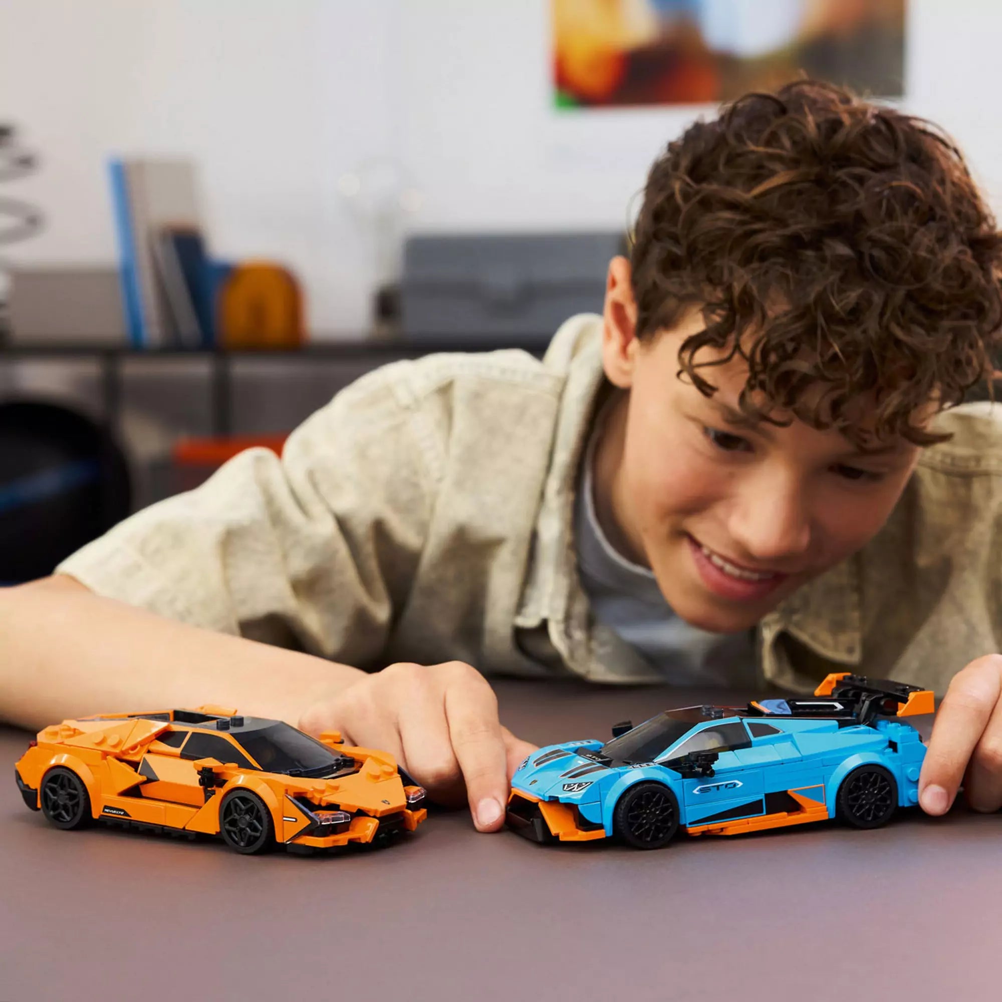  Egy fiú játszik a LEGO Speed Champions 77238 készlet kék és narancssárga Lamborghini autóival az asztalon.