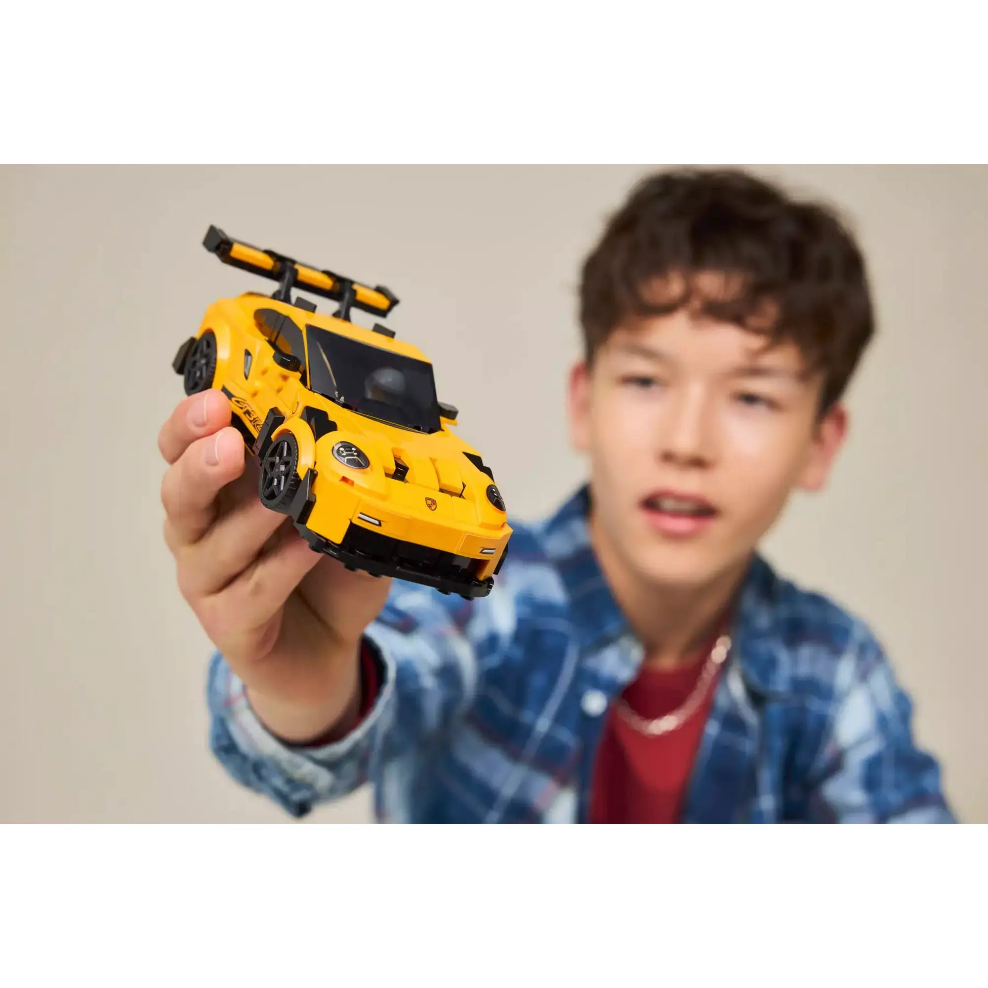 Gyerek kézben tartja a LEGO Porsche 911 GT3 RS (77239) sportautót, bemutatva a játékélményt.
