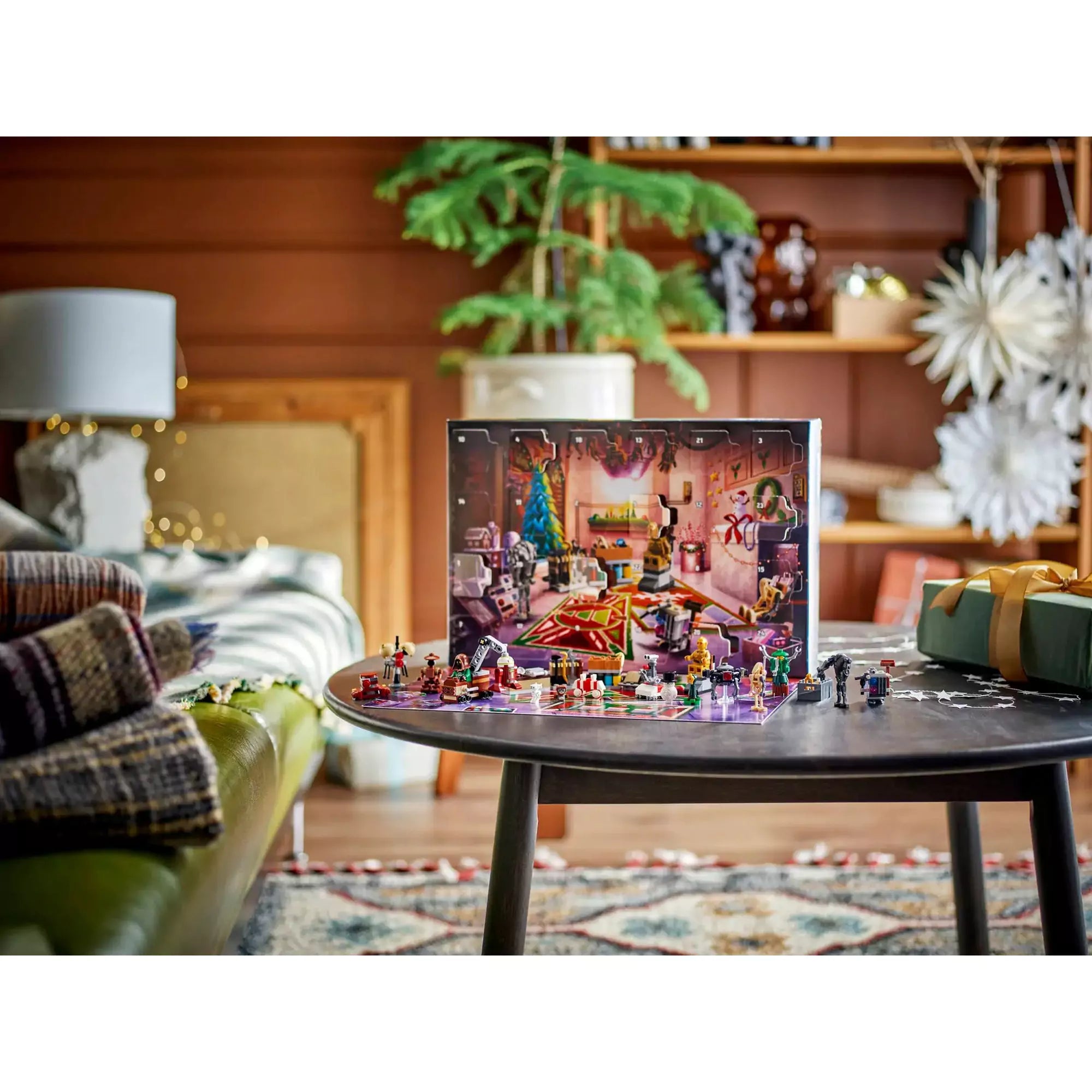 LEGO Star Wars Adventi naptár 2025 kinyitva, karácsonyi dekorációval díszített droidműhely háttérrel, figurákkal és miniépítményekkel egy asztalon.