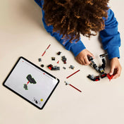 Egy gyerek kék pulcsiban épp összeépíti a LEGO Star Wars Darth Maul Mech (75411) darabjait, mellette egy tablet mutatja a digitális útmutatót.