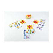 A Meglepi! társasjáték játék közben: asztalon elhelyezett ajándékkártyák és a sárga, piros szalaggal átkötött doboz.