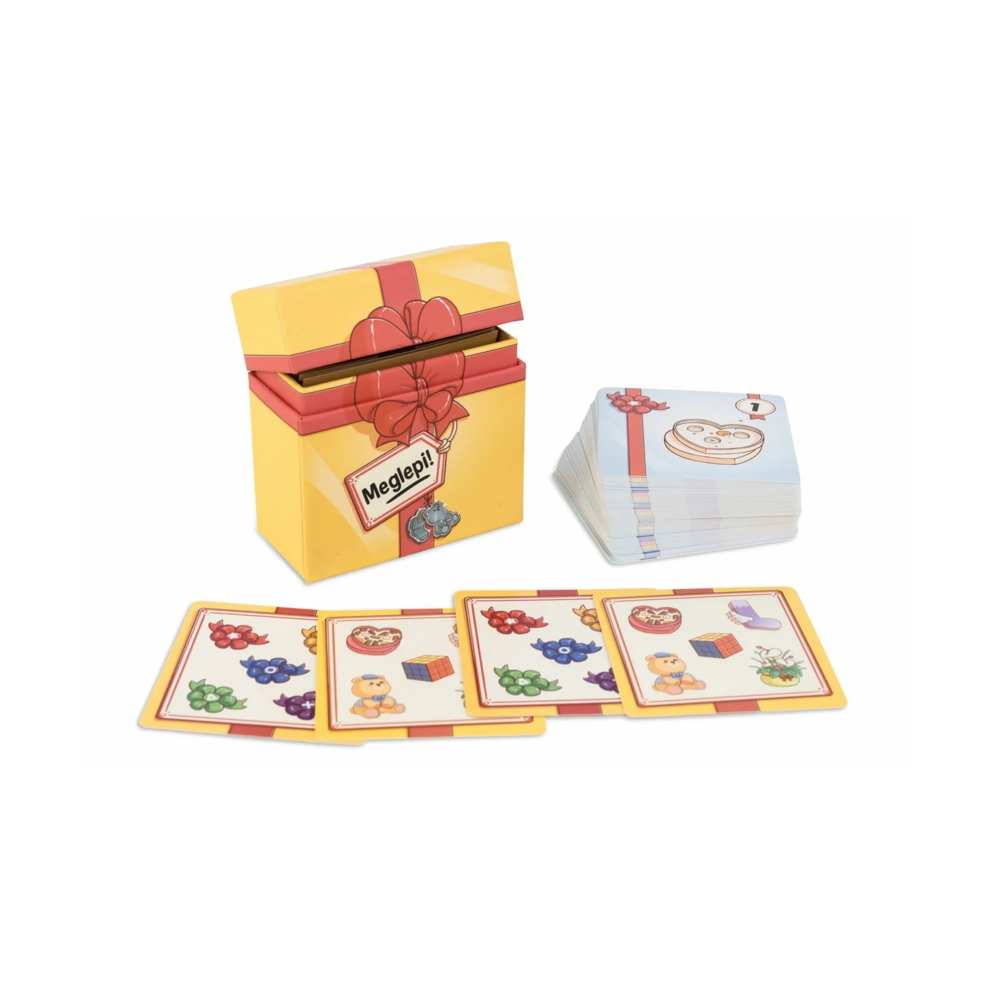 A Meglepi! társasjáték nyitott sárga doboza és a kártyapakli, előtérben kirakott ajándékos illusztrációjú lapokkal.
