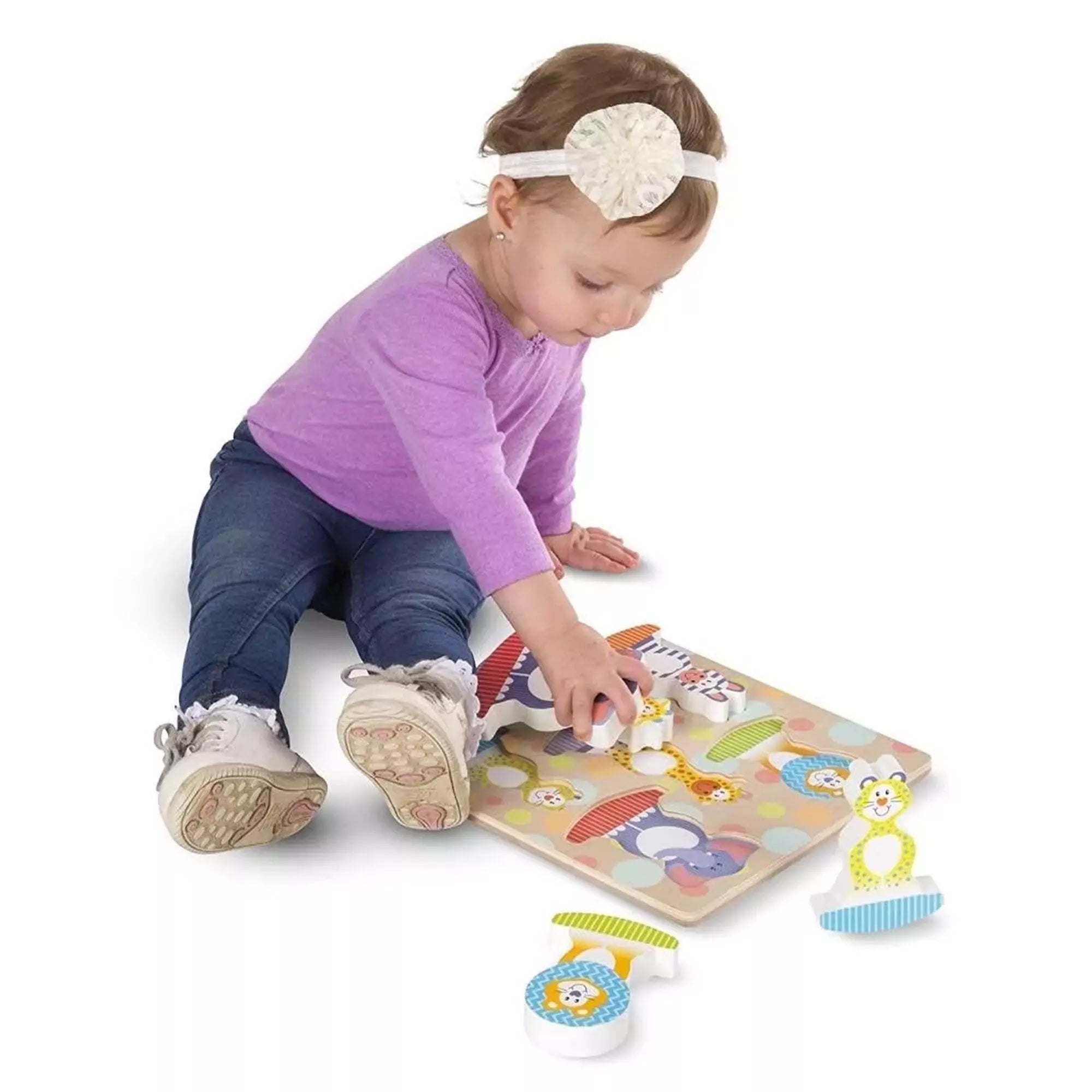 Kisgyermek Melissa & Doug safari fa puzzle elemeivel játszik, színes állatfigurákat helyezve a táblára.