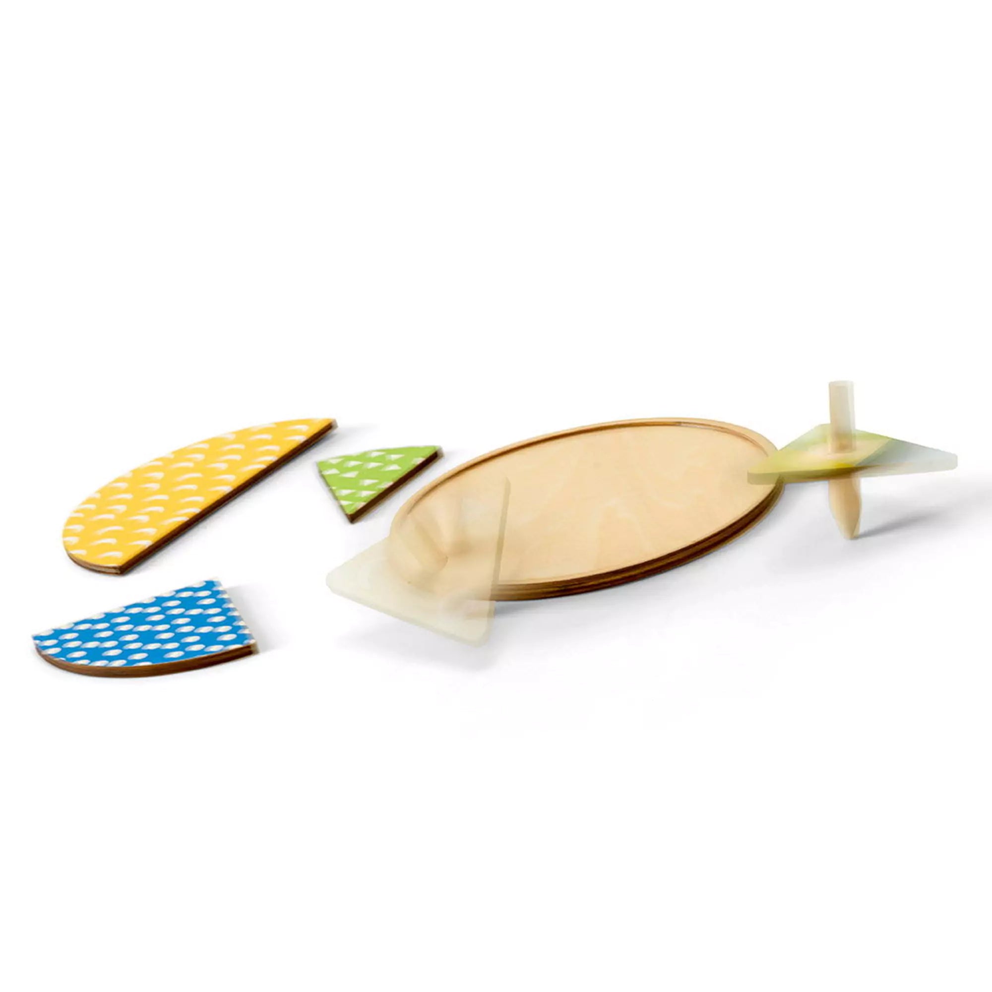 „Pörgetés és párosítás, pörgettyűs játék, BS Toys – fa pörgettyűk és színes puzzle-elemek kör alakú tábla mellett.”