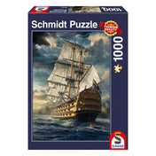 „Puzzle Schmidt: Vitorlás hadihajó – 1000 darabos kirakó doboza, klasszikus angol hadihajóval és viharos tengerrel a háttérben.”