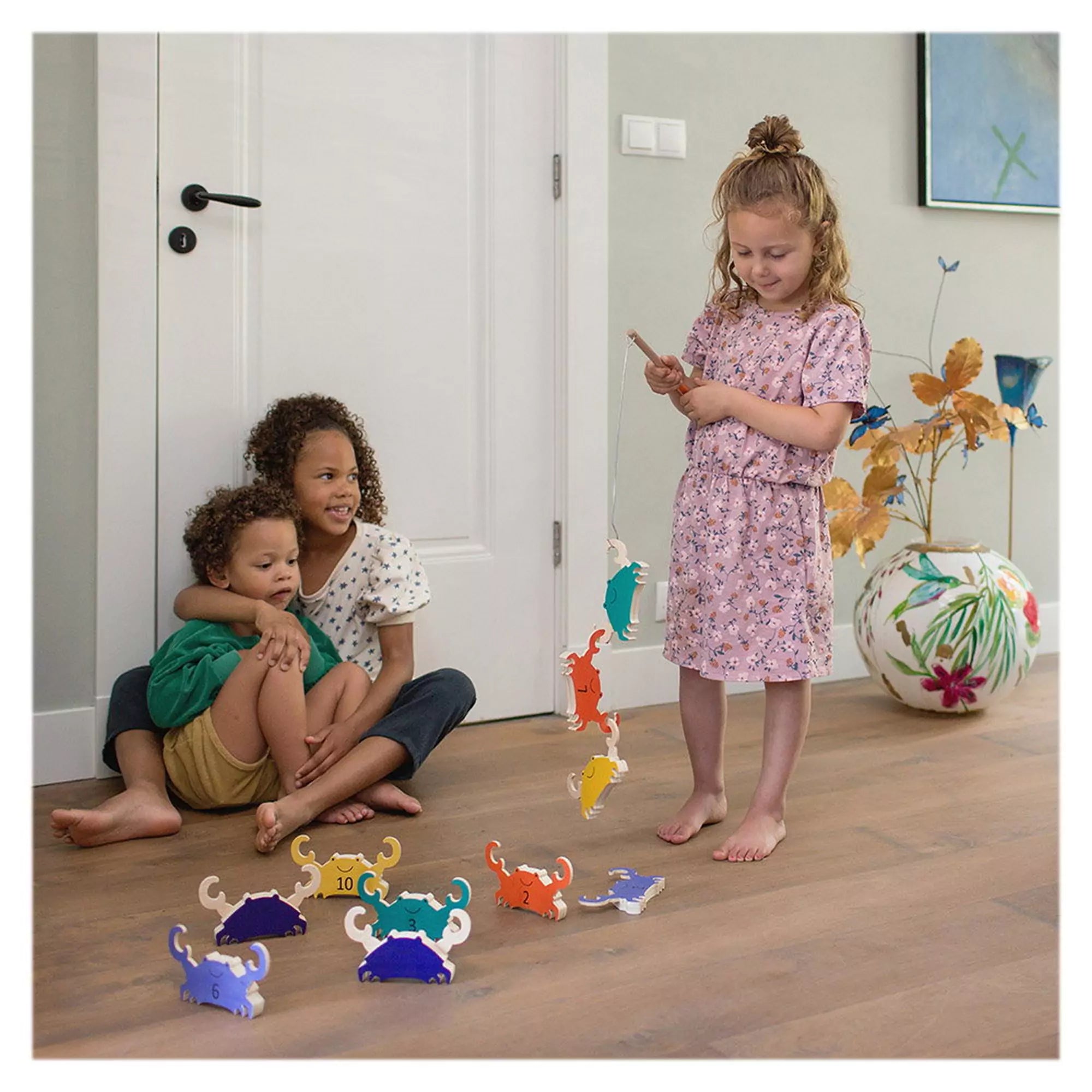 Három gyerek játszik együtt bent a BS Toys Crab Fishing játékkal; egyikük éppen több színes rákot fogott ki egymás után.