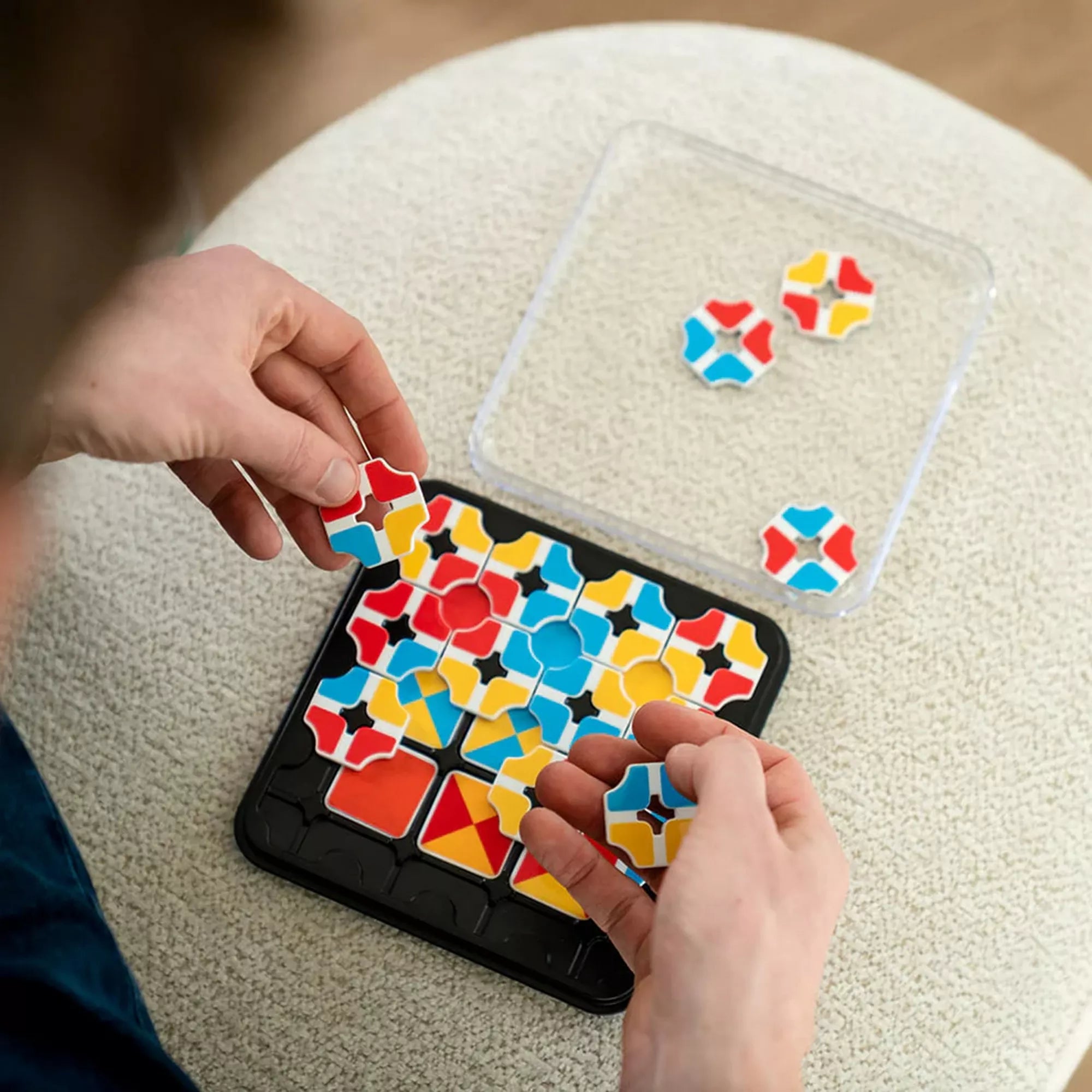 Játék közben használt Smart Games Quantum 2 in 1 kirakó, kézben tartott színes elemekkel.