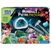 A Minerale și Pietre Prețioase tudományos játékkészlet színes doboza, melyen egy kisfiú nagyítóval figyeli a különféle drágaköveket és ásványokat, a háttérben pedig ragyogó kristályok és feltáró eszközök láthatók.