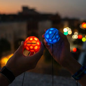 Waboba Moonshine LED labdák kézben tartva, piros és kék színben világítva, városi háttérrel éjszaka.